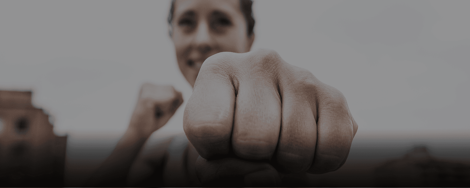 Logo de KO sobre entrenadora sosteniendo una mancuerna con una mano.